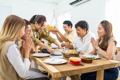 4k group of asian people friends enjoy dinner party eating food and drinking wine on the table with talking together at home. happy man and woman reunion dinner meeting celebration on holiday vacation