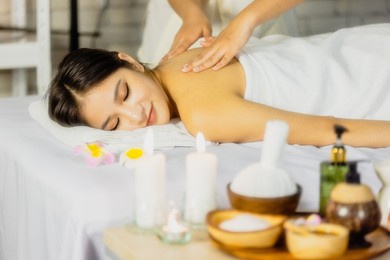 happy relaxing asian girl at beauty spa treatment. beauty young asian woman recieving massage at spa, massager's hands on the woman's shoulder spa concept. young woman with glow, and perfect skin.