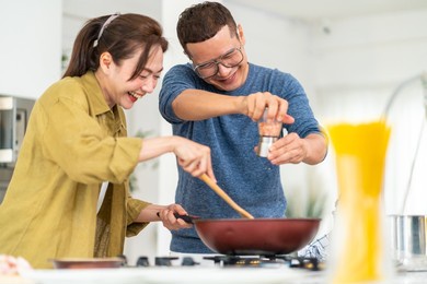 group of smiling asian people friends enjoy cooking with talking together in the kitchen at home. happy man and woman having dinner party meeting celebration eating food together on holiday vacation