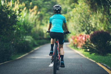 woman cycling on tropical park trail in summer