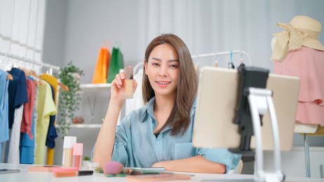young asia woman workin online e-commerce shopping at home. startup online fashion cloth business. set up live streaming by using tablet video call show product to customer. buy and sell concept
