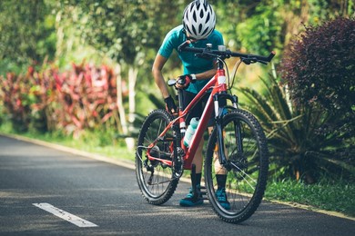 woman cyclist adjust the seat height cycling on summer park trail