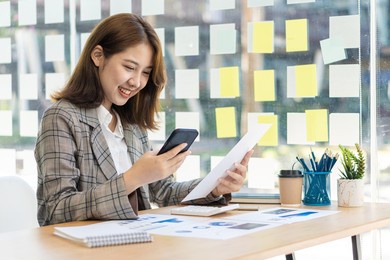 asian woman, self-employed, focusing on mobile phone with the laptop. financial analysis, graphs, accounts, charts, online marketing plans, working concepts based on coffee shops outside the home.