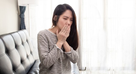 asian beautiful woman are sitting on sofa in living room and coughing. sick and healthy concept