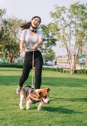 young sporty woman playing with her beagle dog walking with dog leash at park with happy moment at evening time