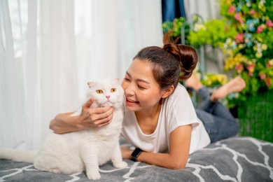 asian pretty girl enjoy to play with cat in living room at home. concept of happiness with pet and love animal.