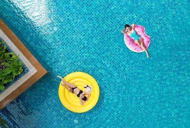 beautiful young asian woman with yellow inflatable ring relaxing in swimming pool. top view