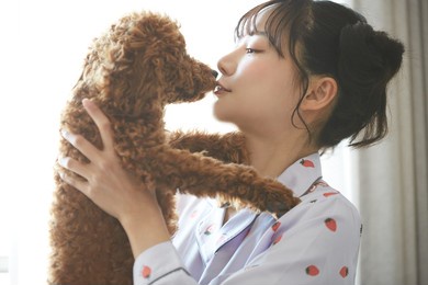 young asian woman in pajamas spending time with her pet.