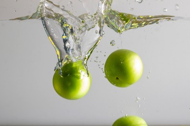  green plum dropping into water and splash of water