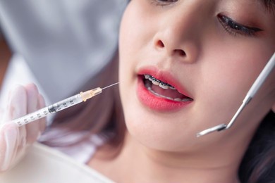 close up mouth female girl having anesthetic injection dental checkup, braces for good teeth hygiene and health with dentist specialist orthodontist using tools checking mouth, hospital surgery room