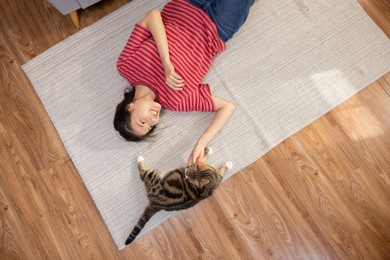 top view of asian woman lying on the floor playing with a cat