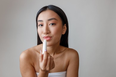 asian young woman using hygienic lipstick in studio