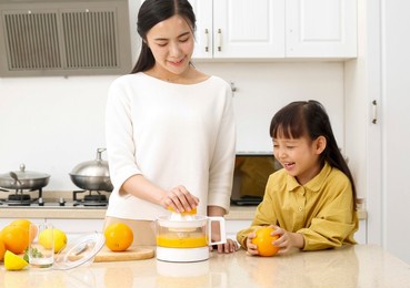 mother feeding daughter orange juice