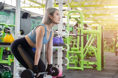 young woman bodybuilder with barbell flexing muscles doing squats in gym. concept of sports, gyms, fitness, bodybuilding. preparing for the competition.
