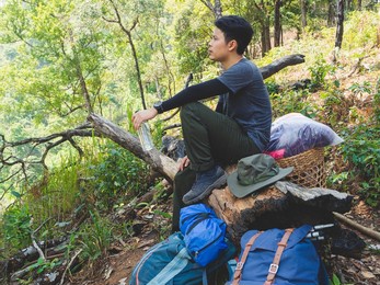 portrait of asian traveler man with backpack on a hiking trip in forest.