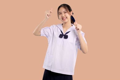 happy braces asian student girl in school uniform smiling on isolated pastel background.