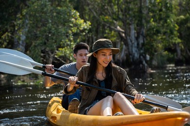 asian attractive romantic young couple rowing kayak in a forest lake. backpacker man and woman travel and kayaking on canoe in beautiful mangrove forest enjoy spend time on holiday vacation together.