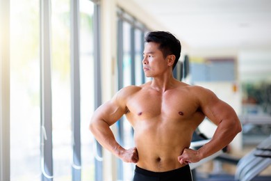 man exercising in gym. asian bodybuilder lifting weights. sport and healthy activity for young male. active chinese athlete in training. body building exercise work out.