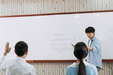 asian male teacher teaching students at the classroom