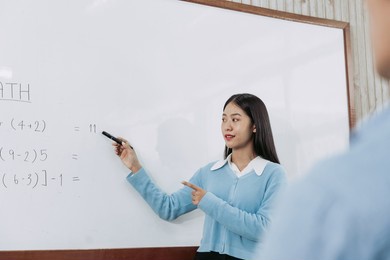 young asian teacher teaching students at classroom.