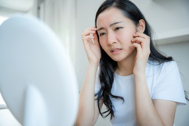 young woman asian are worried about faces dermatology and allergic to steroids in cosmetics. sensitive skin,red face from sunburn, acne,allergic to chemicals,rash on face. skin problems and beauty