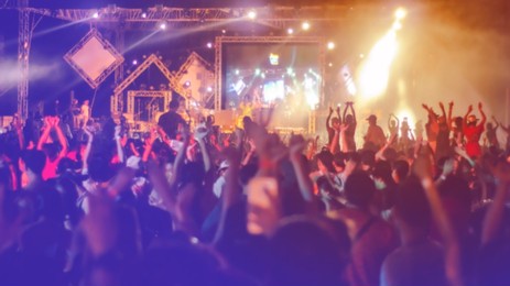 de-focused or blurred concert crowd enjoying the music.crowd raising their hands and enjoying great festival party.young happy people are dancing in club. nightlife and disco concept.