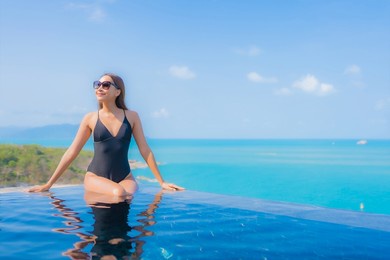 portrait beautiful young asian woman relax smile leisure around outdoor swimming pool in resort hotel with sea ocean view