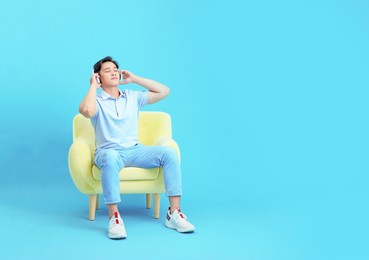 relaxing asian young handsome guy sit on single sofa, use smart phone, isolated on background