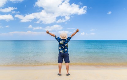 young asian man raise his hands up by the sea, vacation time, happy holiday. freedom concept