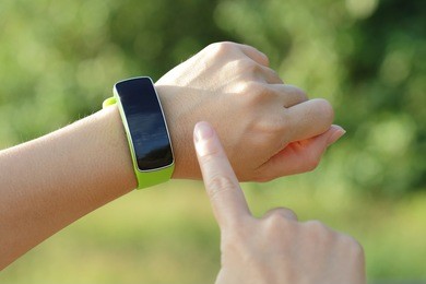 smart watch on hand with empty screen on nature green background, screen is great for your design copy space