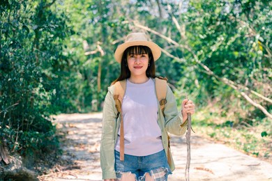 young asian woman explores the forest on holiday. woman walking in a young forest in warm weather.