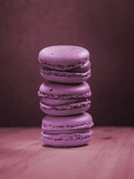 purple macaroons in neon light on wooden board