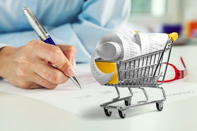 shopping cart and man working on calculator with financial document.  financial crisis concept.
