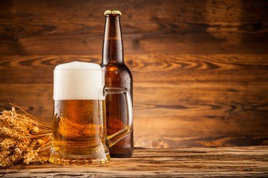 glass and bottle of beer with wheat ears on wooden planks