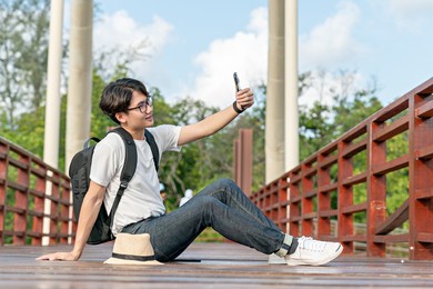 happy man travel mangrove forest. tourist traveler wear white shirt with hat for backpack activity. asian man ready to go hiking. relax time on holiday concept travel.