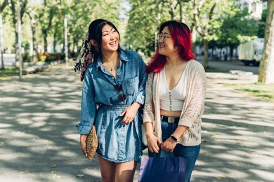 two asian women walking happily through the city. japanese sisters laughing and talking outdoors.