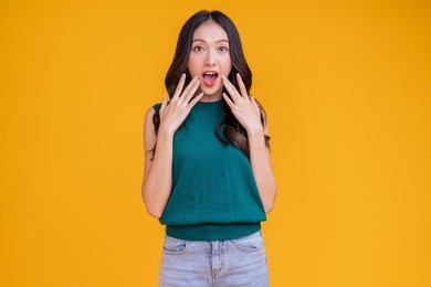 casual happiness asian female woman smiling cheerful in green tshirt blue jean relax peaceful positive thinking carefree lifestyle standing hand gesture face expression with yellow color background 