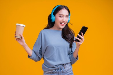 happiness carefree asian female woman teen wearing headphone hand hold coffee cup listen dance joyful fun moving moment ,teen wear casaul cloth singing move while laugh smile trendy lifestyle