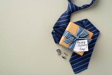 father's day concept. top view photo of craft paper gift box with striped ribbon bow and postcard blue necktie and cufflinks on isolated pastel grey background