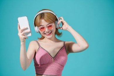 portrait of a joyful woman in dress and make up listening to music with earphones while holding mobile phone