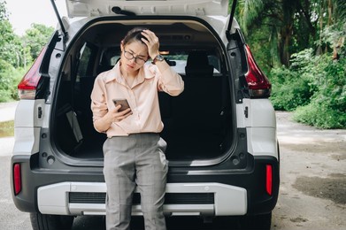 asian woman having problem about her car breakdown and she trying to call insurance or someone to help her. car breakdown it will happen to you at least once in your driving life.