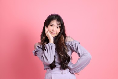 the cute young asian woman with preppy dressed standing on the pink background.