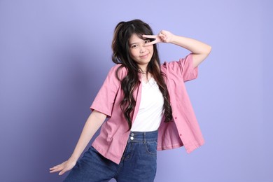 the cute young asian girl with casual clothes standing on the purple background.