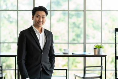 portrait of asian business man wear suit at the office. smiling asian business man standing with background modern office