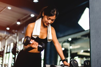 slender asian girl lifts dumbbells and plays steel ball exercise equipment weight lifting equipment exercise equipment in the gym arranged in an orderly line in the gym