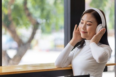 attractive beautiful asian woman wearing headphones enjoying listening to music.