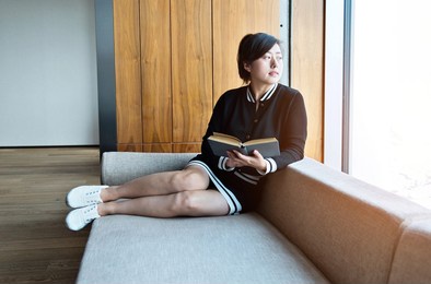 young asian woman white sofa reading a book