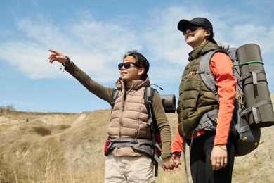 horizontal llow angle of two young asian female friends hiking on spring day somewhere in mountains looking into distance