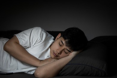 side view of asian man sleeping in his bed with a bright expression on his face at night. concept of health care with at least eight hours of bed rest.