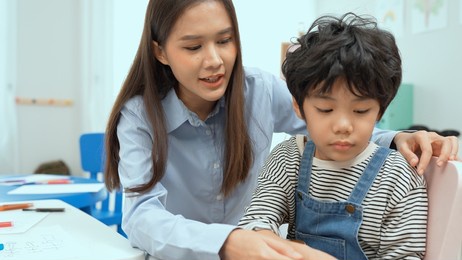 young asian teacher teaching guitar and ukulele to his little boy.little boy learning guitar at kindergarten.close up,ukulele class at school. child learning guitar from her teacher.musical education.